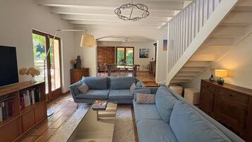 Un salon spacieux, doté d’un grand canapé, d’une table basse et d’un escalier menant à un niveau supérieur.