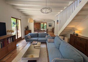 A spacious living room with a large sofa, a coffee table, and a staircase leading to an upper level. - Villa with pool and garden - 30' from Lyon (Saint-Just-Chaleyssin)
