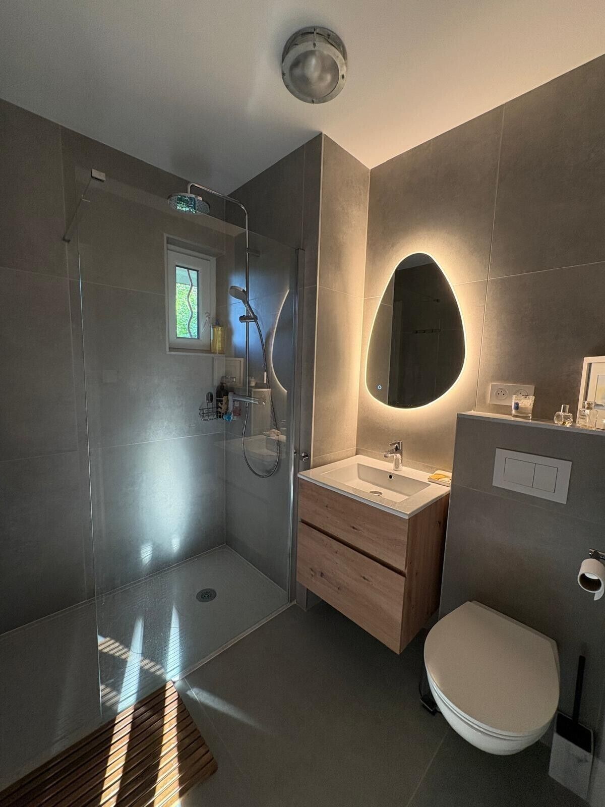 Een moderne badkamer met een inloopdouche, een wastafel met spiegel en een toilet.