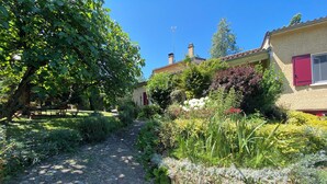 A garden path leading to a house with a red door, surrounded by lush greenery and flowering plants. - Villa with pool and garden - 30' from Lyon (Saint-Just-Chaleyssin)