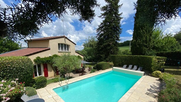 A rectangular swimming pool with a tiled deck, surrounded by greenery and a house with a red door. - Villa with pool and garden - 30' from Lyon (Saint-Just-Chaleyssin)