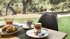 A table with croissants, a cup of coffee, a glass of tea, a jar of honey, and honey dipper. - Uddastri Retreat (Arzachena)