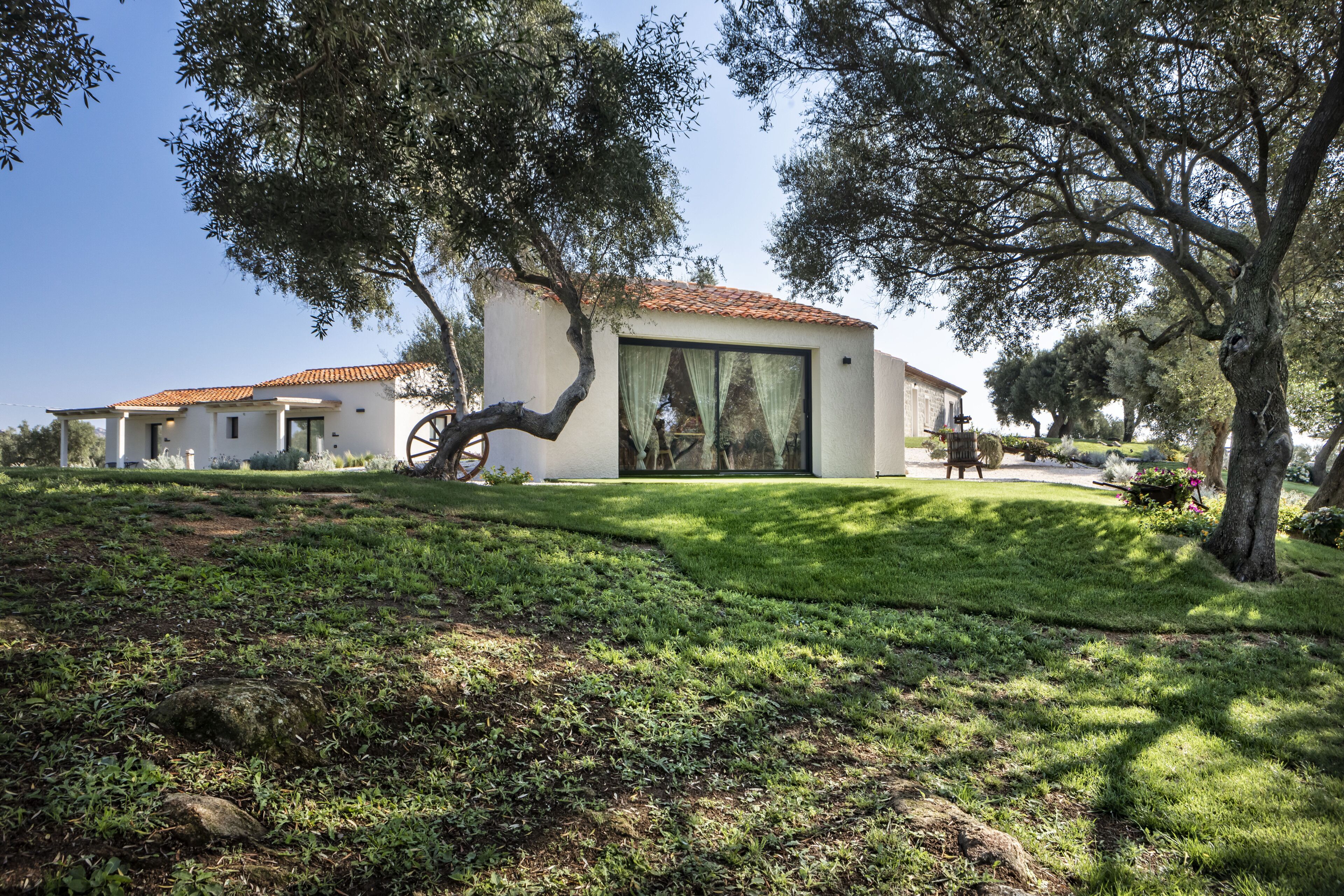 A modern house with a tiled roof, large windows, and a well-maintained lawn.