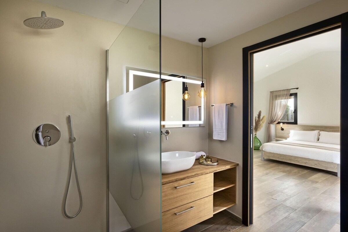 A modern bathroom with a glass shower enclosure, a white sink, and a wooden vanity.