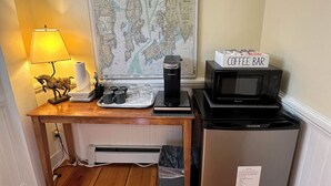 Une petite cuisine équipée d’une machine à café, d’un four à micro-ondes et d’un petit réfrigérateur. Une carte est affichée sur le mur, au-dessus du comptoir.