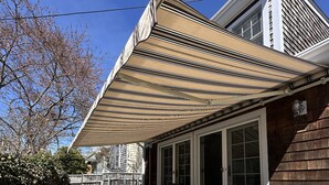 A house with a covered porch, outdoor seating, and a garden with yellow flowers. - Dive into downtown Newport RI in this private, large, unique townhouse-style 2BR apartment at 205 Spring St! King and Full beds + pull-out sofa full kitchen, 2 baths, outdoor patio, AC, TVs, Wifi. Just steps to Thames Street, shops and wharfs (Newport)