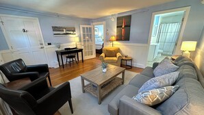 A living room with a sofa, chairs, a coffee table, and a dining area with a table and chairs. - Dive into downtown Newport RI in this private, large, unique townhouse-style 2BR apartment at 205 Spring St! King and Full beds + pull-out sofa full kitchen, 2 baths, outdoor patio, AC, TVs, Wifi. Just steps to Thames Street, shops and wharfs (Newport)