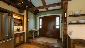 A kitchen with wooden beams, a stainless steel refrigerator, and a wooden door. - Step into historic magic at this renovated post-and-beam loft in downtown Newport RI! Open floor plan, cozy beds, full kitchen, two decks for outdoor dining, mini-split AC, TVs. Steps to Thames Street, shops, wharfs—Superhost (Newport)