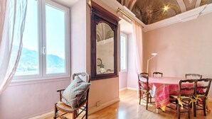 Uma sala de jantar com uma mesa posta para quatro pessoas, cadeiras de madeira, um espelho grande e vista para montanhas pela janela.