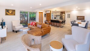 A modern living room with a sofa, chairs, a dining area, and a kitchen. - Newly renovated 3 bedroom, 2.5 bathroom premium holiday home with stunning views (Waiheke Island)
