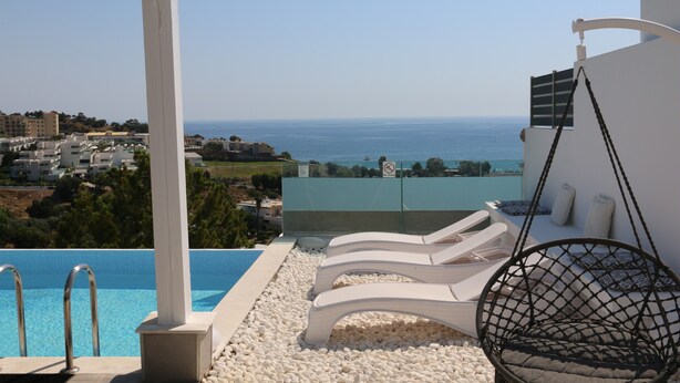 A poolside area with lounge chairs, a hanging chair, and a view of the sea. - Villa *K*  SeaView and Pool. (VLYCHA)