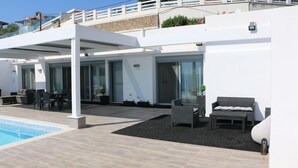 A modern outdoor pool area with a covered seating area, a stone facade, and a white railing. - Villa *K*  SeaView and Pool. (VLYCHA)