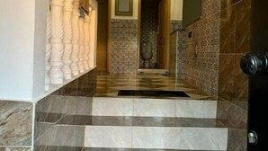 A staircase leading to a room with a chandelier, marble flooring, and a patterned wall.