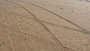 A wide, open sandy beach with a clear blue sky.