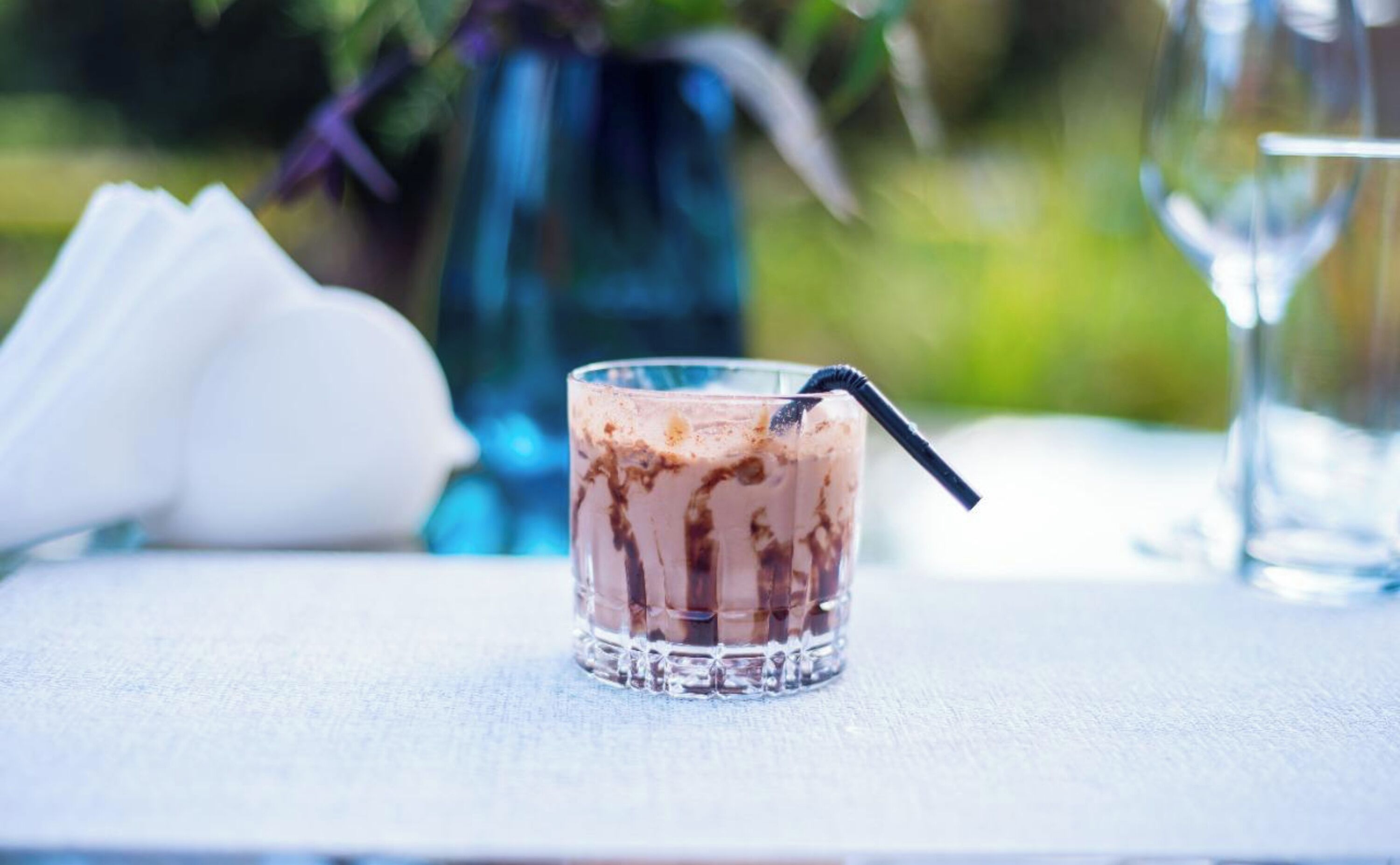 A glass of iced coffee with a straw on a table.