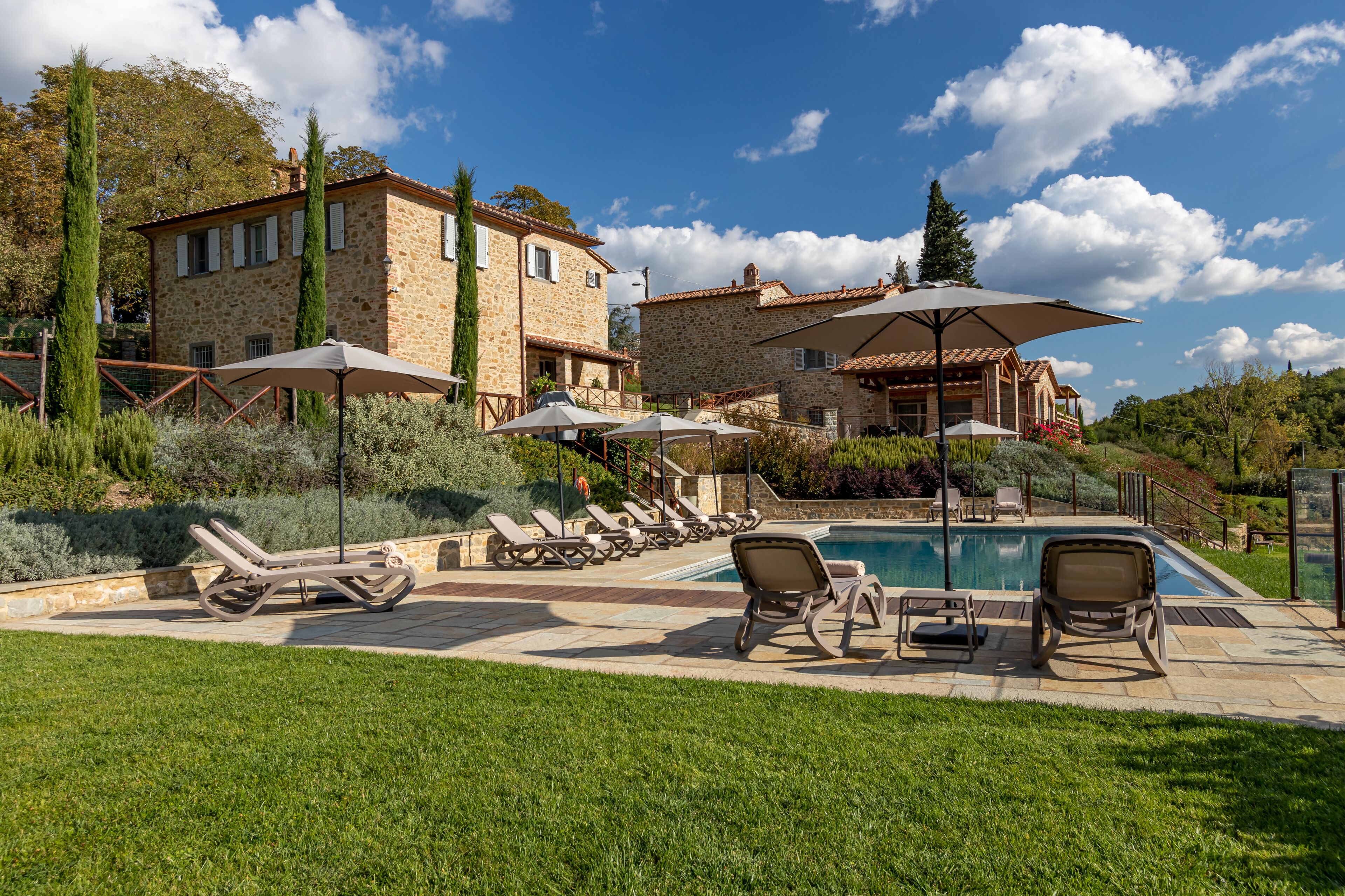 A stone villa with a swimming pool, outdoor seating, and a well-maintained garden.