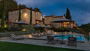 A stone villa with a swimming pool, outdoor seating, and a well-lit patio area. - Chimera Tuscany Resort (Arezzo)