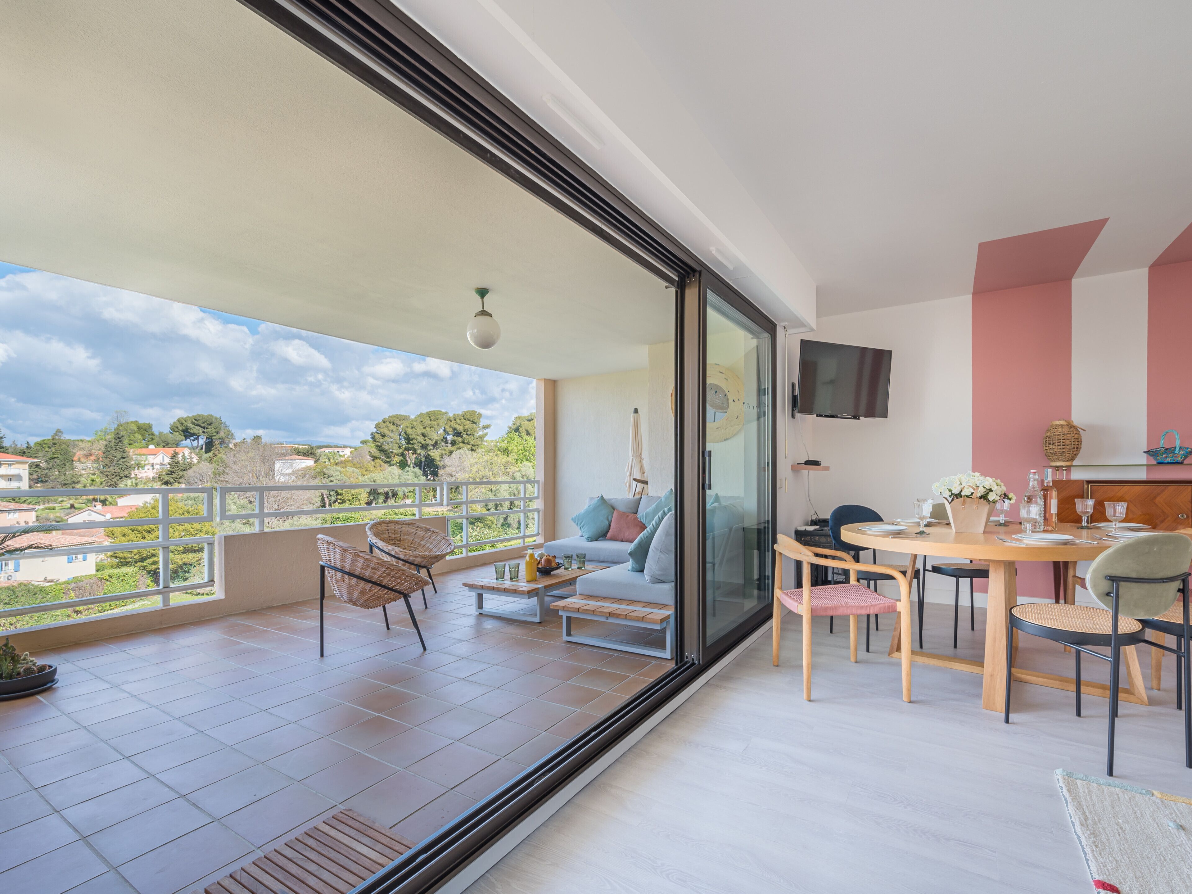 Un balcone con vista sulla città, un'area pranzo con tavolo e sedie, e un divano.