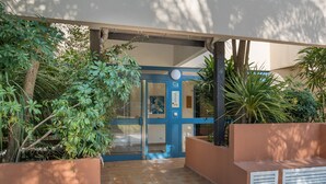 A building entrance with a blue door, surrounded by greenery and a tiled pathway. - LE PARC Apartment for 5 By Sunset (Antibes)