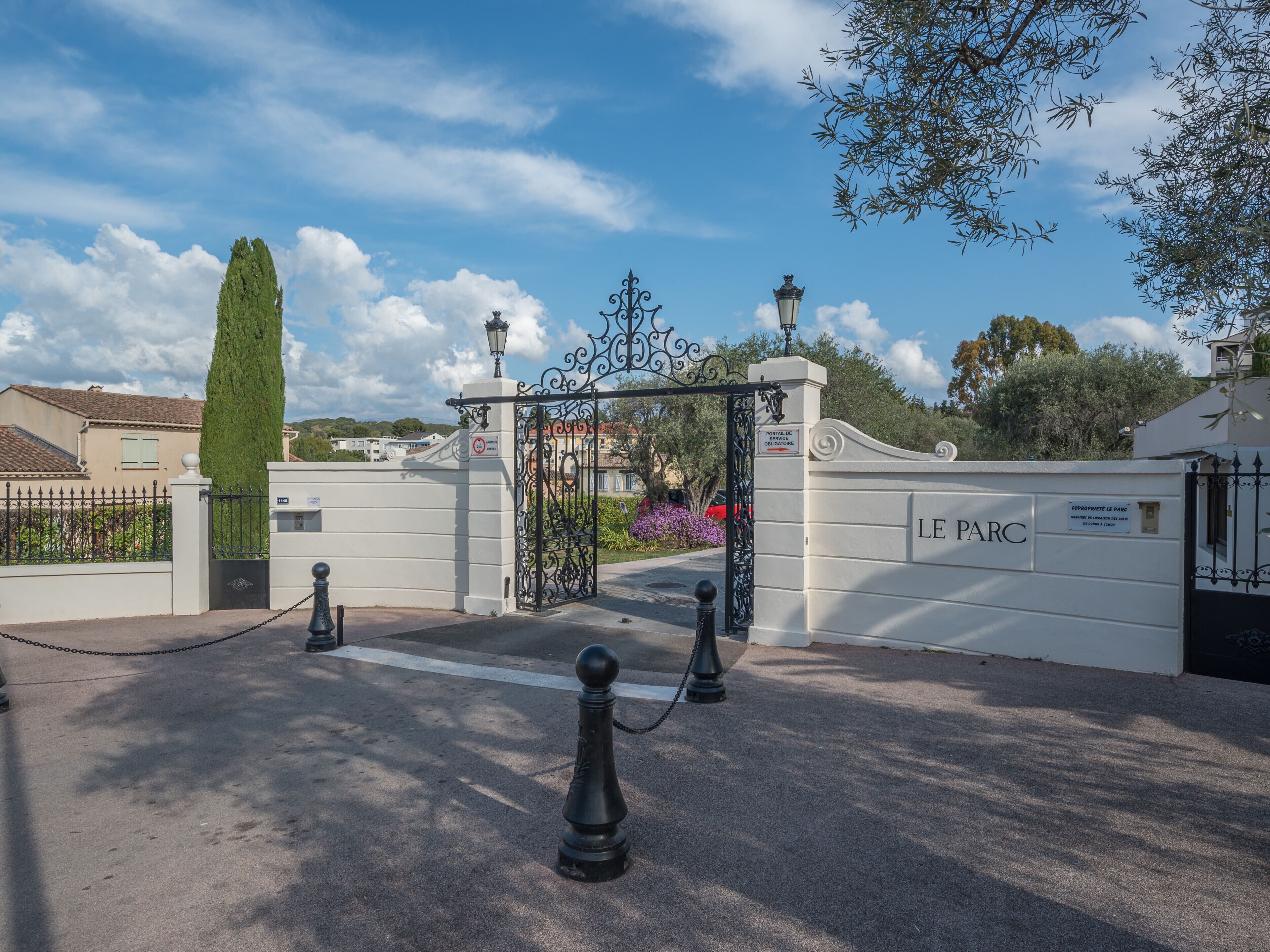 A gated entrance with a sign reading "LE PARC" and a decorative iron gate.