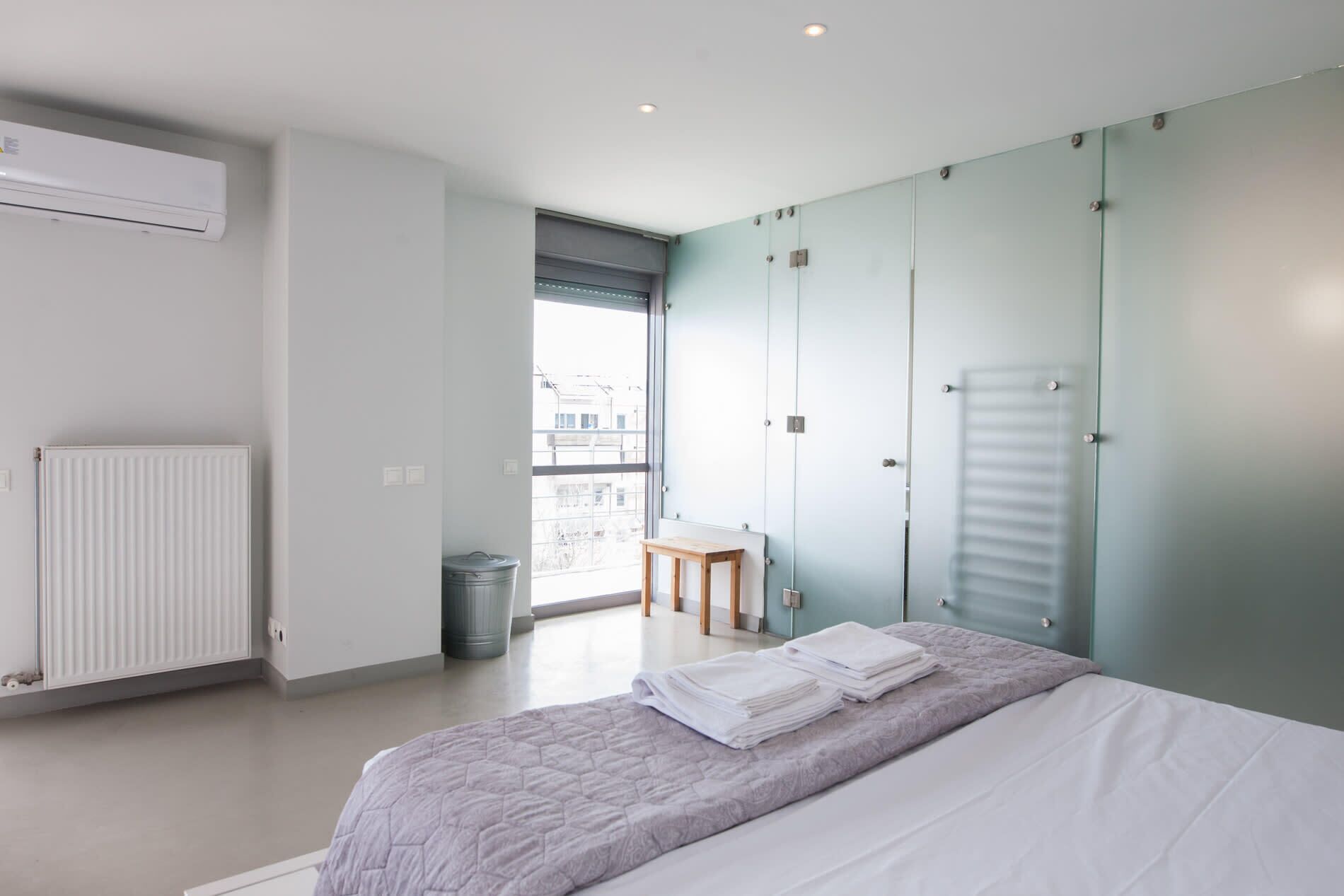 A modern bedroom with a bed, a radiator, a window, and a view of the outside.