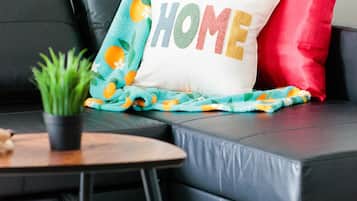 A black leather sofa with a colorful blanket and a pillow with "HOME" text.