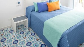 Un dormitorio con una cama, un mesita de noche y dos cuadros colgados en la pared.