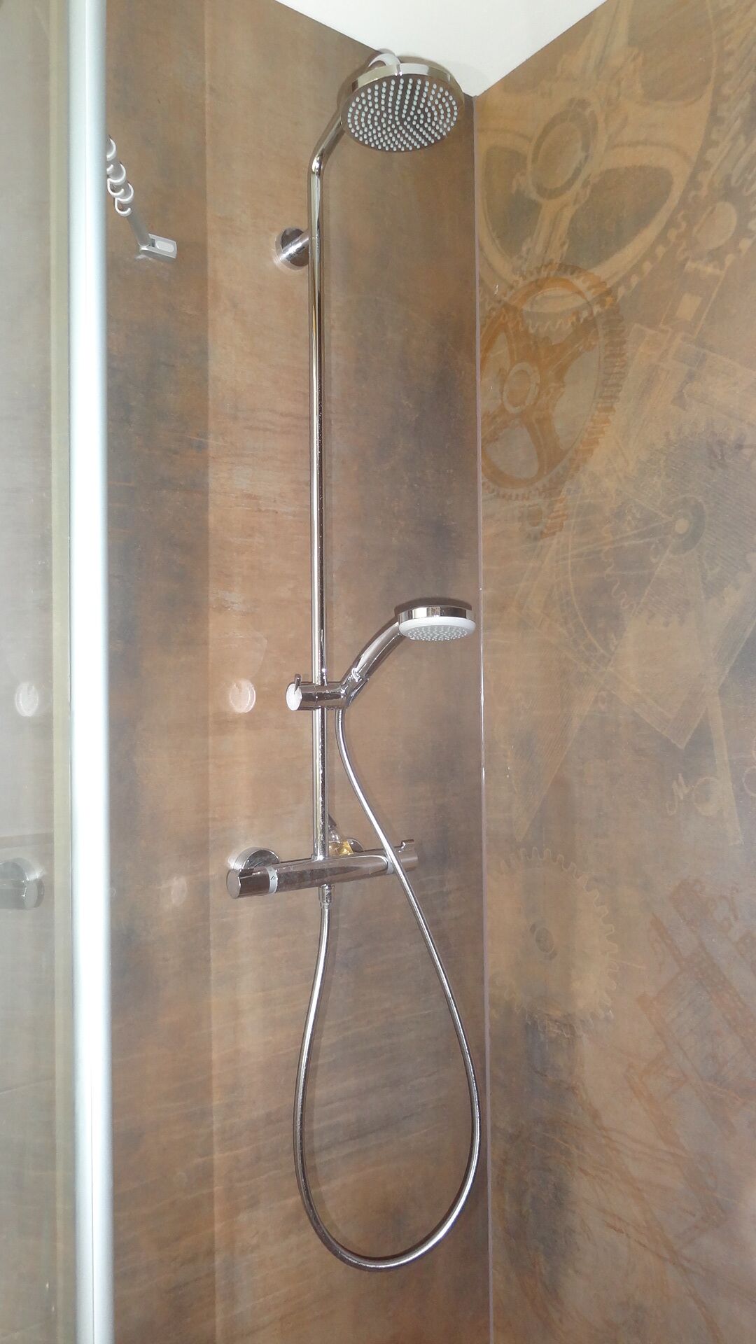 A shower with a handheld showerhead and a wall-mounted faucet.