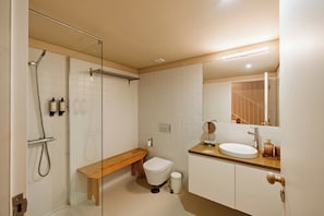 A bathroom with a shower, toilet, bench, and sink. - Porto Vitoria Apartments (Porto)