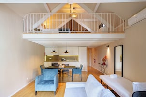 A modern interior with a dining area, sofas, a balcony, and a kitchen.
