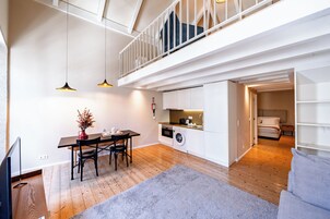 A modern apartment with a dining area, kitchen, and a loft bedroom.