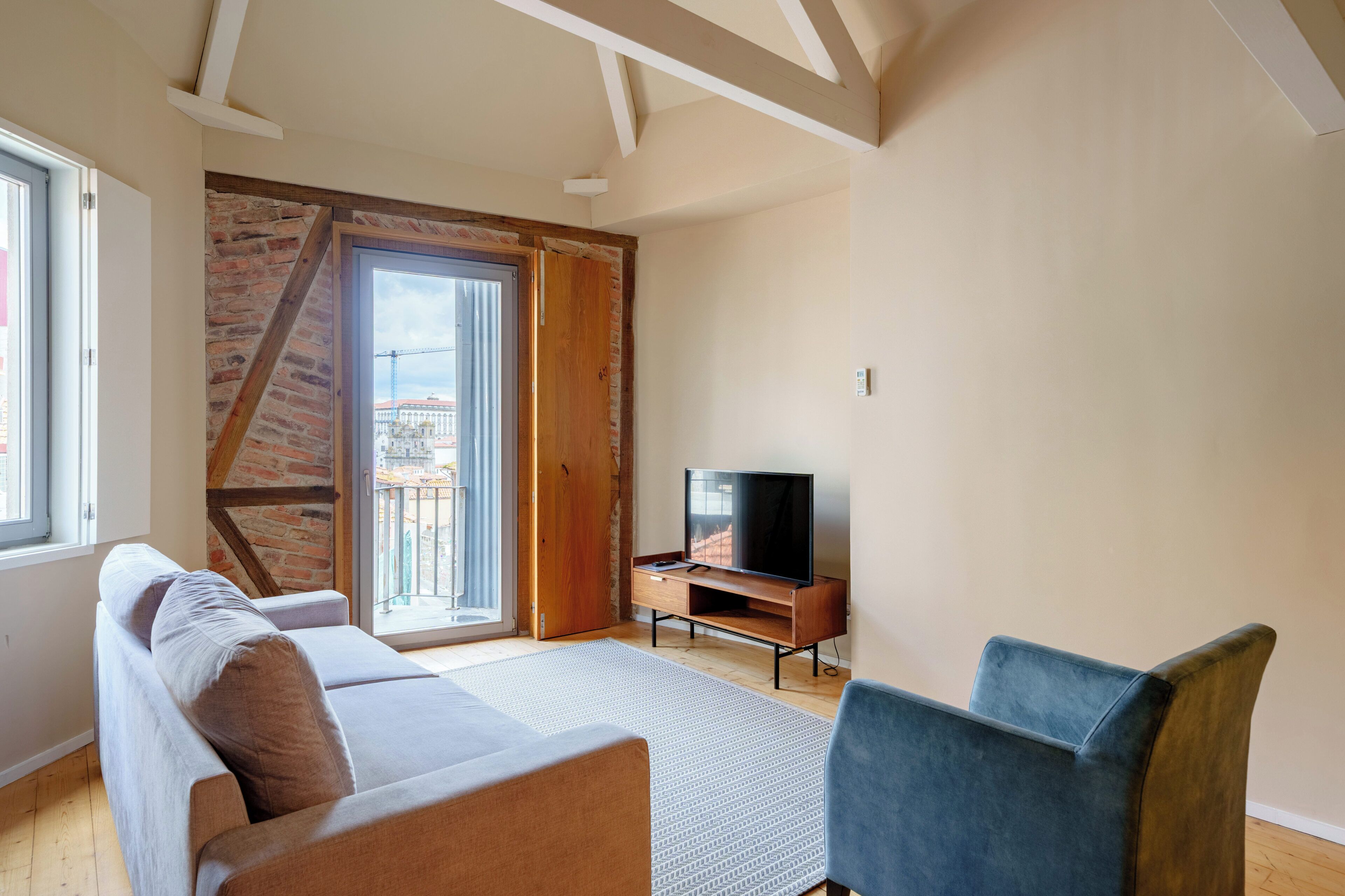 Una sala de estar moderna con un sofá, un televisor y vistas a un balcón.