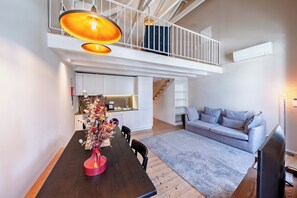 Um espaço moderno para viver com área de refeições, cozinha e um quarto no mezanino.