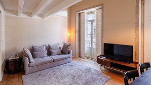 A living room with a sofa, a TV, a coffee table, and a fireplace. - Porto Vitoria Apartments (Porto)