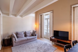 A living room with a sofa, a TV, a coffee table, and a fireplace. - Porto Vitoria Apartments (Porto)