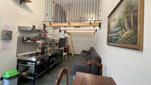 A compact kitchen with a gas stove, sink, and various kitchen utensils. A lofted sleeping area with a wooden ladder is above the kitchen.