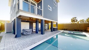 Ein modernes, zweistöckiges Haus mit überdachter Terrasse und Swimmingpool.