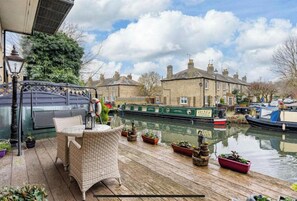 A riverside patio with wicker furniture, potted plants, and a canal view. - Hertford - Sleeps 2 - 92 Walking Score - Garden (Hertford)