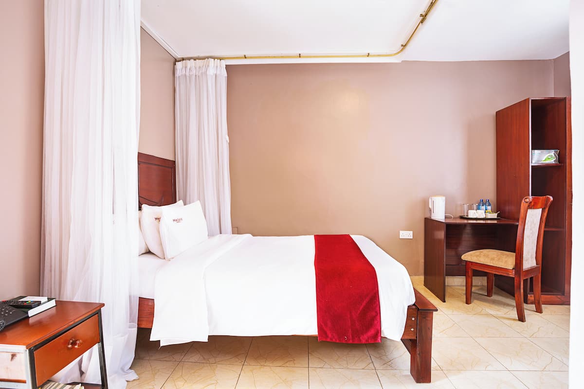 Ein Hotelzimmer mit Bett, Schreibtisch, Stuhl und Kleiderschrank.