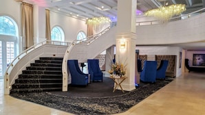 A grand lobby with a marble staircase, blue upholstered seating, chandeliers, and a 'Hello' sign on a table. - NEWLY RENOVATED! 4 Bed 3 Bath Bachelorette Beach Pad w/ Stunning Views 2 Pools! - 903 (Miami Beach)