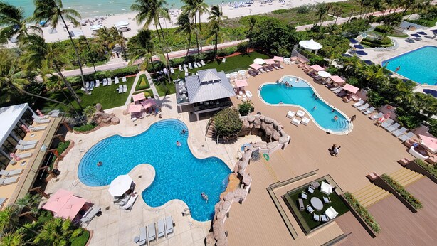 A resort with multiple swimming pools, sun loungers, and palm trees. - NEWLY RENOVATED! 4 Bed 3 Bath Bachelorette Beach Pad w/ Stunning Views 2 Pools! - 903 (Miami Beach)