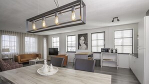Una sala moderna con una mesa de comedor de madera, un sofá y un televisor.