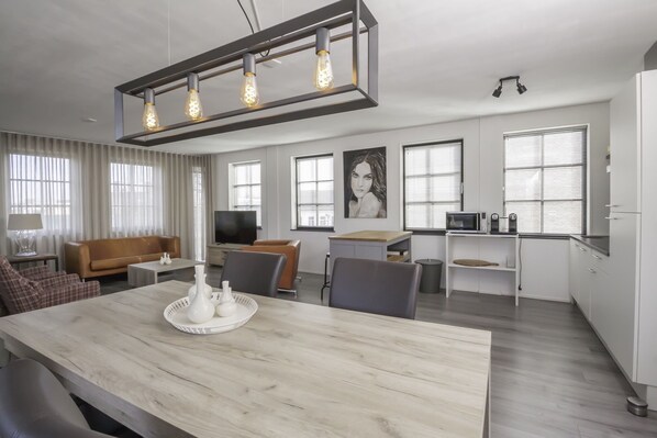 A modern living room with a wooden dining table, a sofa, and a TV.