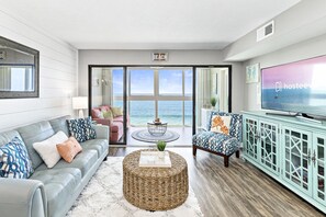 A modern living room with a view of the ocean, featuring a sofa, a coffee table, and a television. - Edgewater West 63 (Gulf Shores)