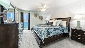 Ein Schlafzimmer mit Bett, Schminktisch, Nachttisch und Blick auf den Ozean.