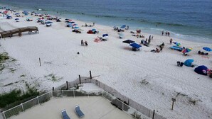 Ein Strand mit Sonnenschirmen, Liegestühlen und einem eingezäunten Bereich mit einer Holzterrasse.