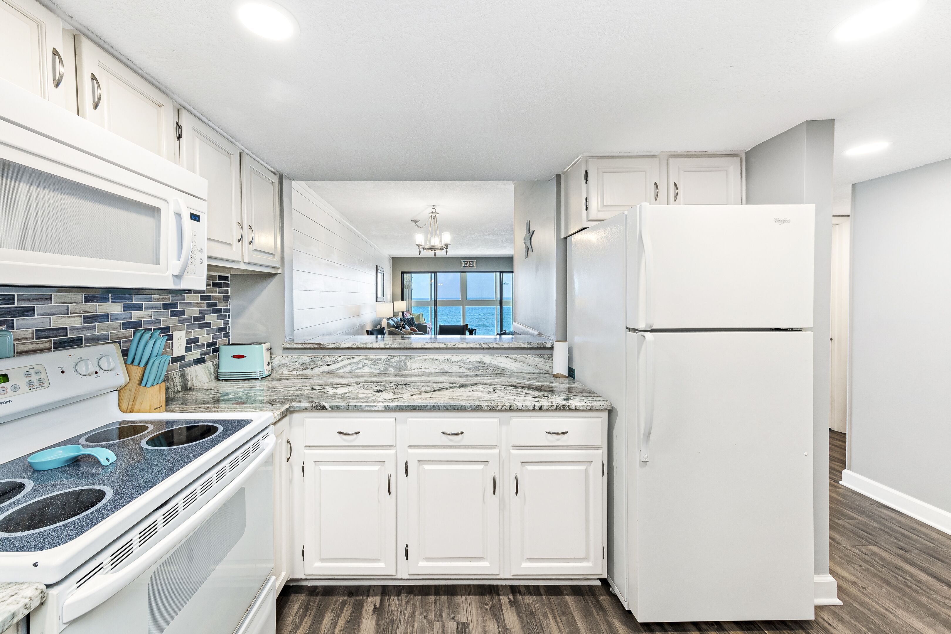 A modern kitchen with white cabinets, a granite countertop, a built-in microwave, and a stainless steel stove.