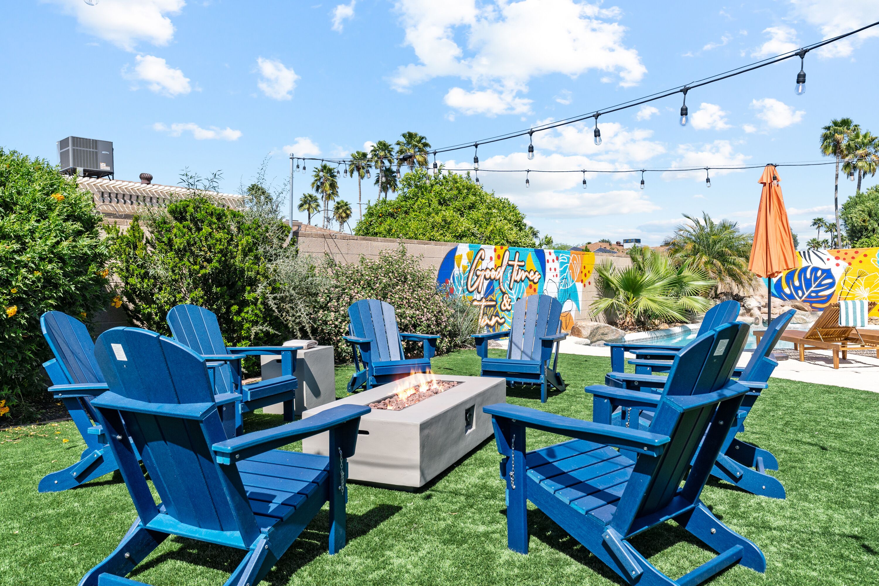 An outdoor seating area with blue Adirondack chairs and a fire pit.