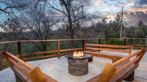 Una terraza exterior con un hogar a leña de piedra y bancos de madera.