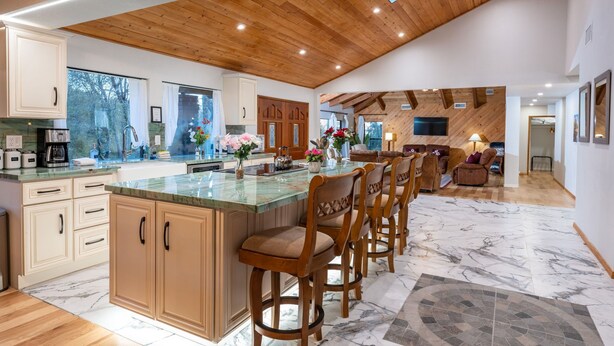 Una cocina amplia con una isla grande, techo de madera y piso de mármol.